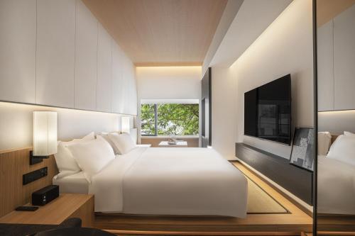 a bedroom with a white bed and a television at Hill Design Hotel 山丘设计师酒店 春熙路太古里店 in Chengdu