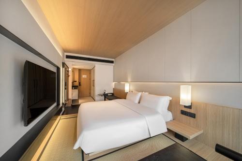 a bedroom with a white bed and a flat screen tv at Hill Design Hotel 山丘设计师酒店 春熙路太古里店 in Chengdu