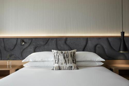a bedroom with a white bed with a large headboard at Kimpton Sawyer Hotel by IHG in Sacramento