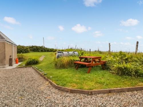 a picnic table in the grass next to a field at Maari in Trumisgarry