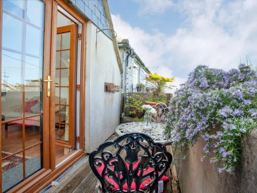 a table and chair on a balcony with flowers at Wheal Trenwith Cottage in St Ives