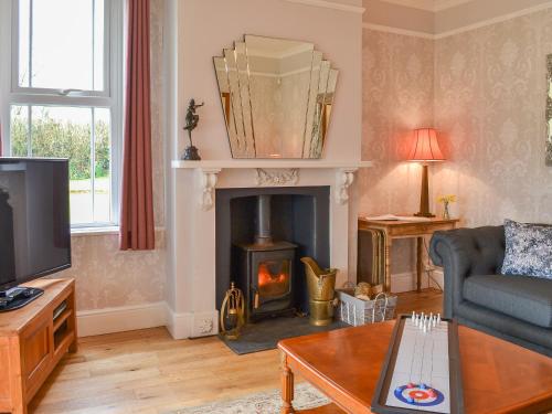 a living room with a fireplace and a couch at Cranford House in Woolfardisworthy