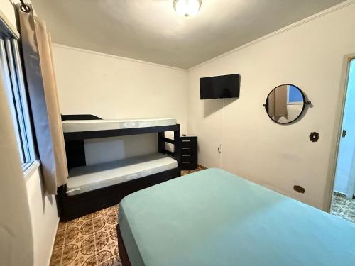 a small room with a bed and a mirror at Pé na Areia Praia da Guilhermina VI in Praia Grande
