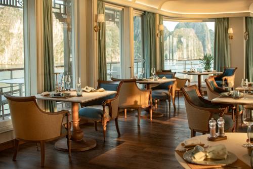 a restaurant with tables and chairs and windows at Bhaya Soul Cruise in Ha Long