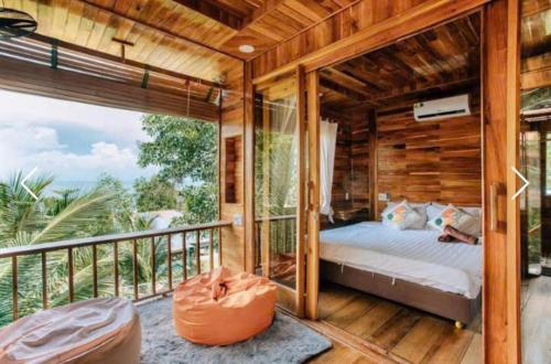 um quarto de madeira com uma cama na varanda em Jade Mountain Bungalow - Sea Breeze - Infinity Pool em Duong Dong