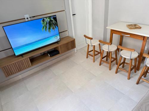 a living room with a television and a table and chairs at Pé na Areia Praia do Gonzaguinha II in São Vicente