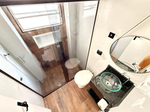 a bathroom with a shower and a toilet and a mirror at Pé na Areia Praia do Gonzaguinha II in São Vicente
