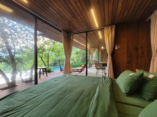 una camera da letto con un letto grande e una grande finestra di Làng Nhỏ - Hồ Láng Nhớt Resort with Nature Life a Nha Trang