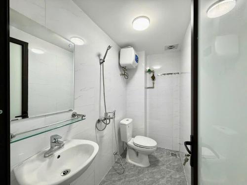 a white bathroom with a toilet and a sink at Hea Home in Hanoi