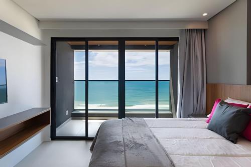 a bedroom with a bed with a view of the ocean at ART STUDIO VISTA Mar FRONTAL ARMAÇAO PITUBA in Salvador