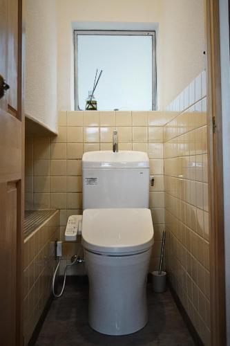 a bathroom with a toilet with a window in it at hotorino in Numazu