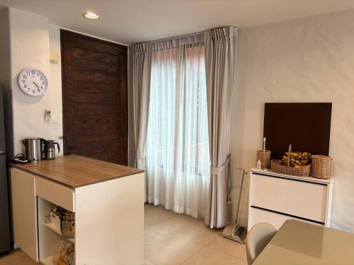 a kitchen with a table and a window with a clock at Playa Hua Hin 3BR Oceanfront in Khao Tao