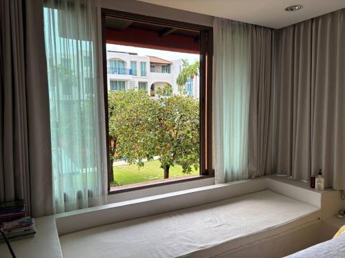 a window in a bedroom looking out at a tree at Playa Hua Hin 3BR Oceanfront in Khao Tao