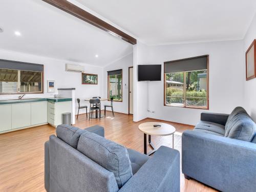a living room with two blue couches and a kitchen at Rockingham Holiday Village in Rockingham