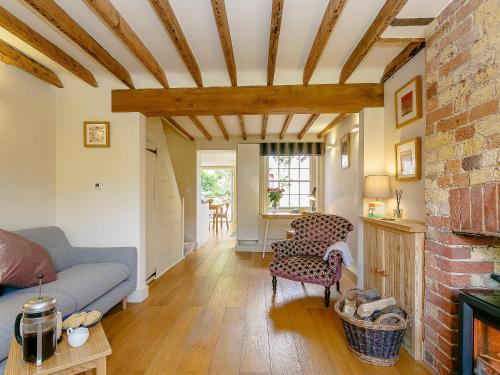 a living room with a couch and a brick wall at Rose Cottage in Poynings