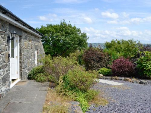 a stone house with a pathway leading into a garden at Sgubor Ucha in Trefriw