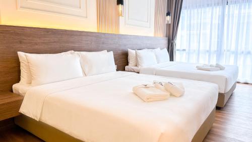 two beds in a hotel room with towels on them at Cottonhouz by Ayuhouz in Kota Kinabalu