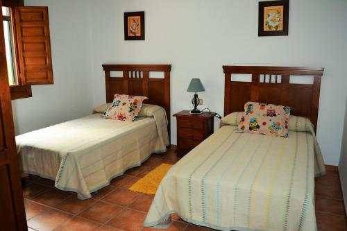 a bedroom with two beds and a lamp on a table at El Emigrante in El Chorro