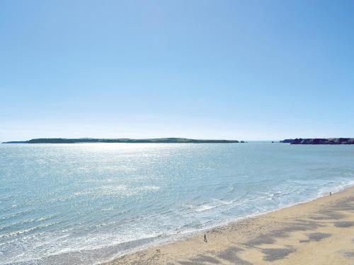 a beach with the ocean and an island in the distance at Pendine Beach Apartment in Pendine