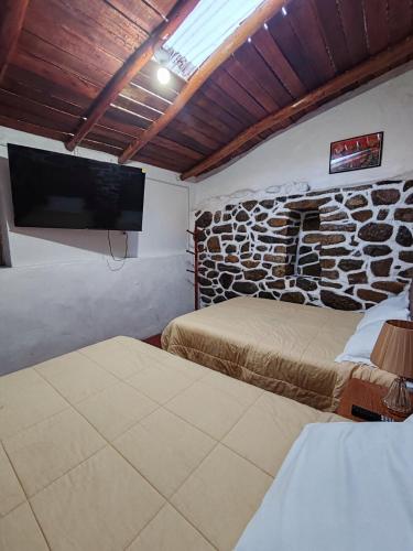 una camera con due letti e una TV a schermo piatto di Muros Incas y Vista Montaña Mini departamento en Ollantaytambo a Ollantaytambo