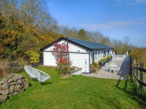 a white building with a table and chairs in a yard at The Lodge in Dyserth