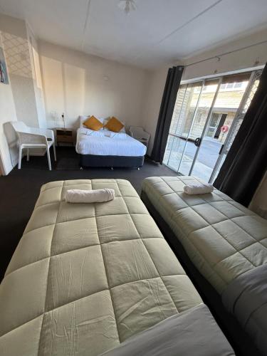two beds in a room with a window at La Maison in Rotorua