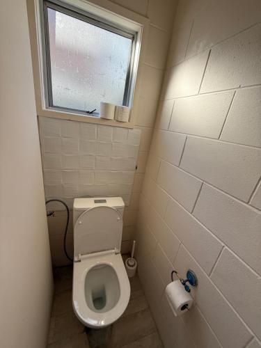a small bathroom with a toilet and a window at La Maison in Rotorua