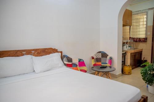 a bedroom with a bed and two chairs and a kitchen at Serene Apartments - studio 001 in Mombasa