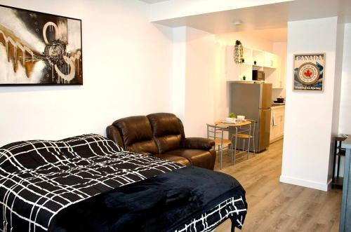 Cozy Bachelor Suite with Kitchenette - Near Downtown في سودبيري: غرفة نوم بسرير وكرسي جلدي