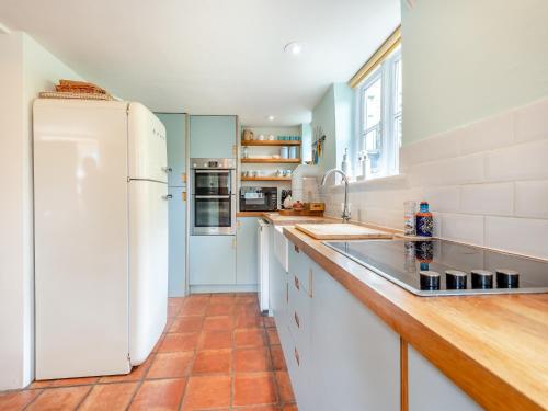 a kitchen with a white refrigerator and wooden counter tops at Church House Cottage in East Stour
