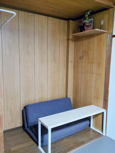 Un sofá y una mesa en una habitación con paredes de madera. en Smile Guest House, en Higashiōsaka