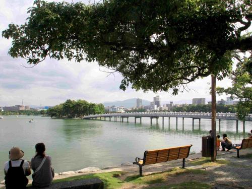 a group of people sitting on a bench looking at a river at Tokyu Stay Hakata in Fukuoka