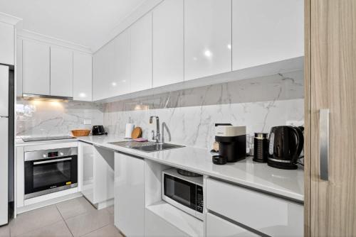 a white kitchen with white counters and appliances at Stylish Rockingham Getaway 2BR Coastal Apartment in Rockingham