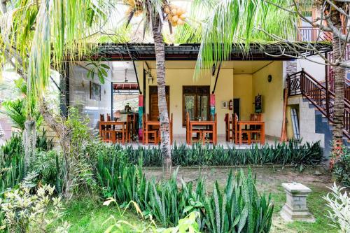 a house with chairs and tables in a garden at RedDoorz Plus @ Singaraja in Singaraja