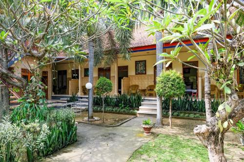 a house with palm trees in front of it at RedDoorz Plus @ Singaraja in Singaraja