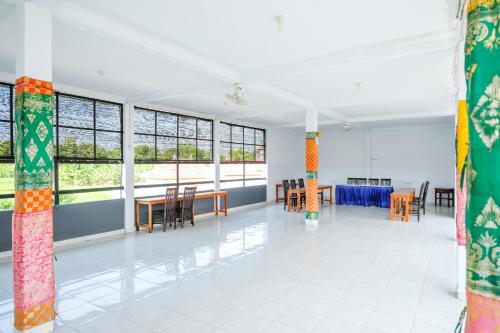 an empty room with tables and chairs and windows at RedDoorz Plus @ Singaraja in Singaraja