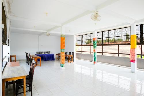 a room with tables and chairs and windows at RedDoorz Plus @ Singaraja in Singaraja