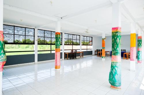 a large room with columns with tables and windows at RedDoorz Plus @ Singaraja in Singaraja