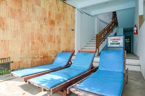 two blue benches sitting in a room with a staircase at RedDoorz Plus @ Singaraja in Singaraja