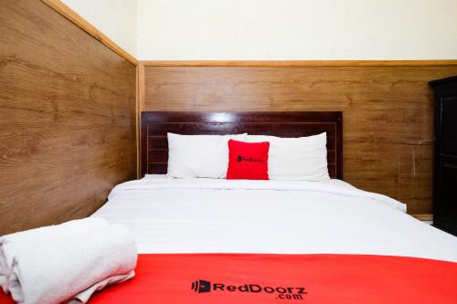 a bedroom with a white bed with a red pillow at RedDoorz Plus @ Singaraja in Singaraja