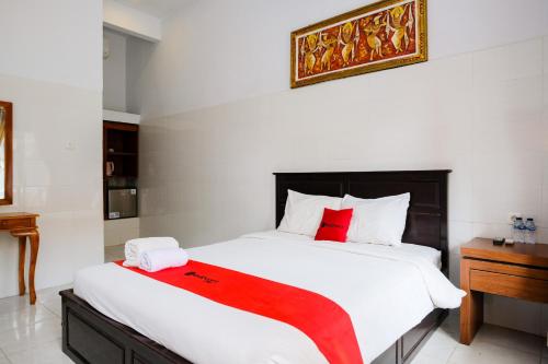 a bedroom with a large white bed with red pillows at RedDoorz Plus @ Singaraja in Singaraja