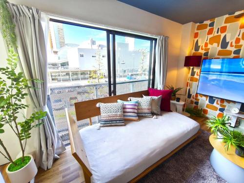 a room with a bed and a large window at simasimaｰstay高松駅フロント in Takamatsu