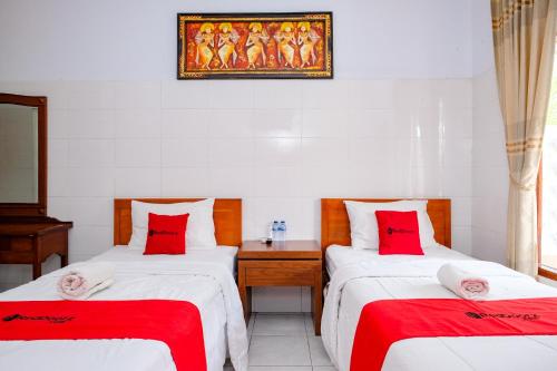 a room with two beds with red pillows at RedDoorz Plus @ Singaraja in Singaraja