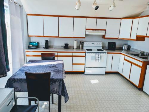 a kitchen with white cabinets and a table and a stove at Alert Bay, Spacious Executive Suite with Panoramic Ocean Views in Alert Bay