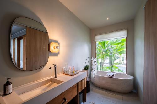 a bathroom with a tub and a large mirror at Anam Tang New Rooms & Cafe near Seminyak in Seminyak