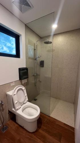 a bathroom with a toilet and a glass shower at Aimo Villa in Ciburial