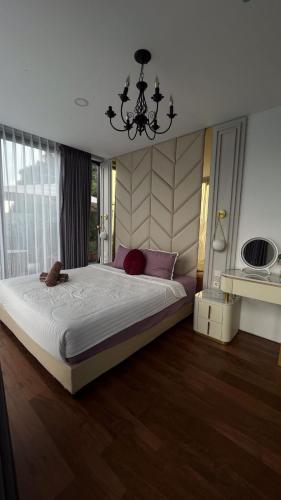 a bedroom with a large bed and a chandelier at Aimo Villa in Ciburial