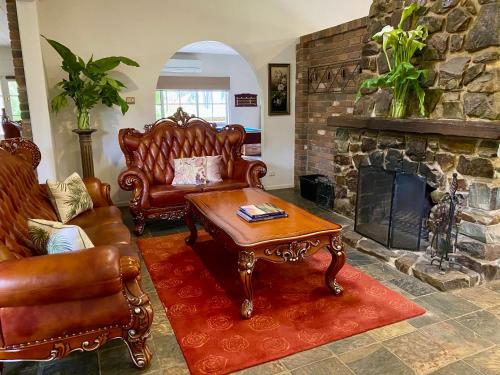 a living room with leather furniture and a stone fireplace at Mornington Peninsula Farmhouse in Main Ridge