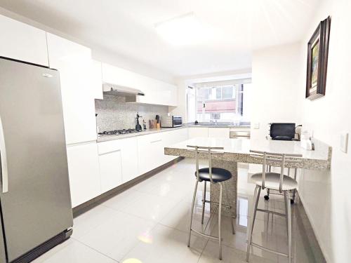 a kitchen with white cabinets and bar stools at Leonora 2 MaiaHomeUbicacion Privilegiada 4BR 3BA en Polanco in Mexico City