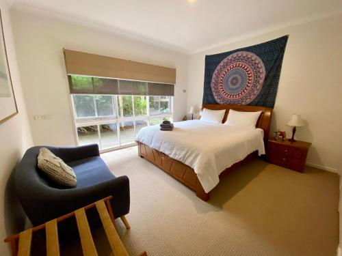 a bedroom with a bed and a chair and a window at Mornington Peninsula Farmhouse in Main Ridge